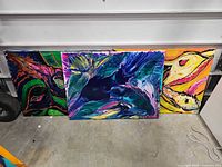 Front view of the three large abstract paintings leaning against wall