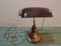 Front view of brass-tone banker lamp showing overall form and cord