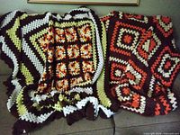 Both afghans draped over sofa showing full patterns and colours