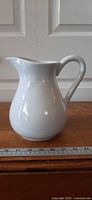 Right side view of white ironstone pitcher with ruler for scale