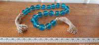 Full garland laid straight with ruler showing length, blue glass beads and jute tassels visible