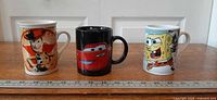 Group shot of all three character mugs next to ruler