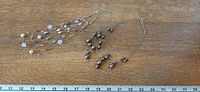 Both necklaces laid out beside ruler showing relative lengths and strand arrangement