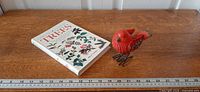 Book and bird statue on wooden surface with ruler for scale