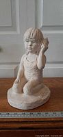 Full frontal view of plaster sculpture with ruler for scale