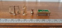 All four brass miniatures lined beside ruler