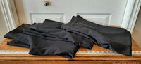 All three pairs of black dress pants folded on table with ruler for scale