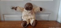 Full frontal view of doll seated against door