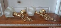 Pair of brass candle sconces with frosted glass shades on wooden surface