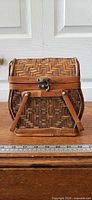 Front view showing woven pattern, latch, handles, ruler for scale