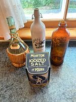 Three vintage bottles and Morton salt box displayed on countertop