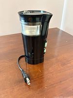 Front view of black Mr. Coffee electric grinder with cord and clear lid