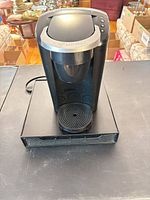 Front view of Keurig coffee maker sitting atop black mesh drawer stand