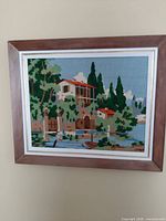Overall view of handmade needlepoint cottage scene in wood frame