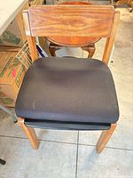 Front view of oak dining chair with black vinyl seat