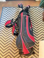 Full view of black/red stand bag with clubs and strap