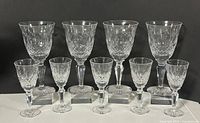 Front view showing all 9 stemware pieces: 4 water goblets back row, 5 sherry glasses front row