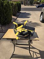 Overall view of black air hose wound on black reel with yellow crank handle and frame