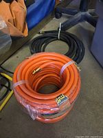 Orange Amflo hose in wrap next to coiled black hose