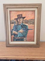 Framed portrait of Clint Eastwood holding revolvers, signature visible