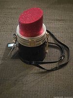Full view of lipstick-shaped purse with strap attached
