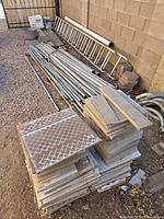 Ladder, tile stack, pipes, bricks, buckets against wall