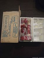 Outer box with DECOTEL branding next to phone in styrofoam