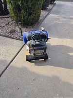 Overall view of Nikota blue-tank electric air compressor on driveway