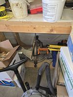 Ridgid sliding compound miter saw on shelf with boxes and vacuum hose, extra blade visible nearby