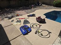Full layout of scuba gear near pool showing fins, BCD, regulators, gloves, boots, snorkel and bag