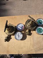 Two Victor brass regulators and four gauges on tabletop