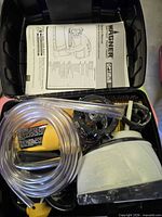 Open carry case showing sprayer, hose, paint cup and manual