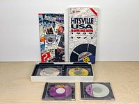 Front view of slipcase, open tray showing two discs, two jewel-cased discs, booklet cover visible
