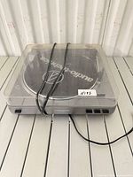 Full view of turntable with dust cover closed, cables bundled on top