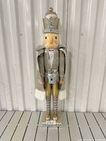 Front view of gold/silver/white wooden nutcracker on glitter base