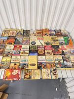 Overview of entire lot spread across table showing roughly 40 paperback books