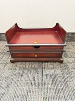 Front view of closed jewelry box showing mahogany finish and brass knob