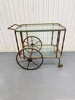 Left side view of two-tier brass faux bamboo bar cart showing handle, wheels, shelves