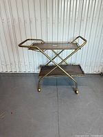 Front view of two-tier brass and wood bar cart with casters