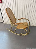 Side view showing full rocking chair profile, metal frame, cane seat/back