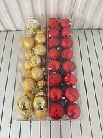 Two clear boxes containing red and gold ornaments