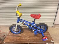 Right side view of Paw Patrol Chase 12-inch bike showing frame, wheels, saddle, pedals, training wheels