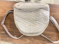 front view showing quilted exterior, gold logo, zipper pocket