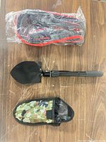 Shovel folded, camouflage pouch, jumper cables in plastic