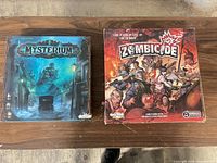 Mysterium and Zombicide game boxes side by side on table