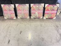 Four framed prints, three in bubble wrap, one fully visible showing abstract design