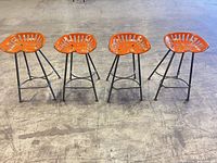 front view showing four orange tractor seat stools