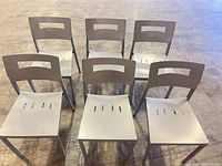 Front angle view of six matching silver-gray metal chairs