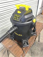 Full view of Stanley wet/dry vacuum showing body, top handle, hose, casters