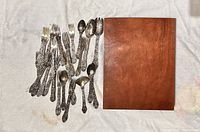 All loose flatware pieces beside closed wooden case